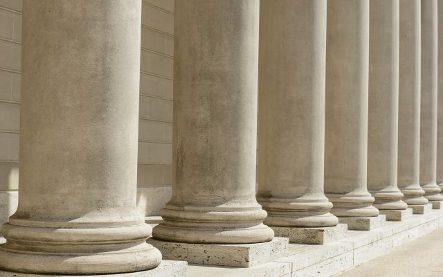 Fila di colonne in pietra, simbolo di forza, struttura e professionalità, che rappresentano i servizi e le soluzioni linguistiche legali.