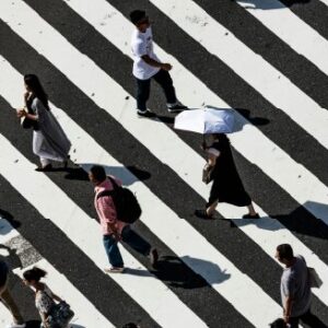 Vista dall’alto di persone che attraversano un attraversamento pedonale a strisce in città, a rappresentare la diversità urbana, il movimento culturale e l’interconnessione globale. Corso di Maka su intelligenza emotiva e sociale