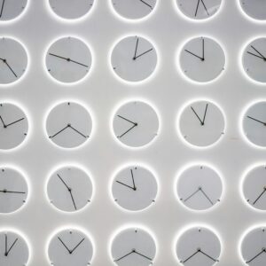 A Wall of white clocks with different times, symbolizing the power of routine and how to optimize your time with good habit management.
