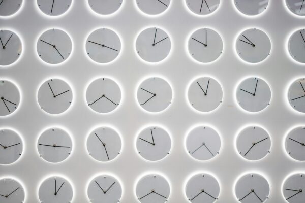 A Wall of white clocks with different times, symbolizing the power of routine and how to optimize your time with good habit management.