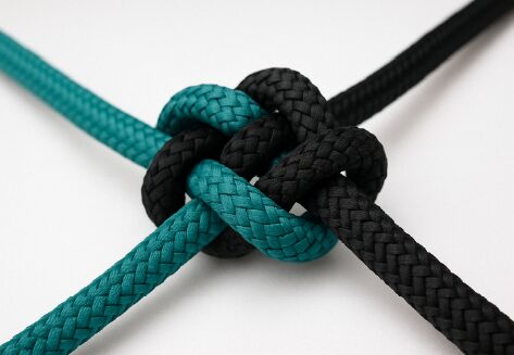 Close-up of black and teal ropes tied in a strong knot, symbolizing unity and resolution in Maka's Conflict Management course.