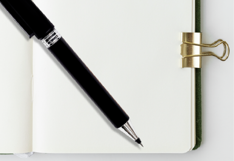 Una penna nera appoggiata in diagonale su un quaderno aperto, tenuto fermo da una clip dorata.